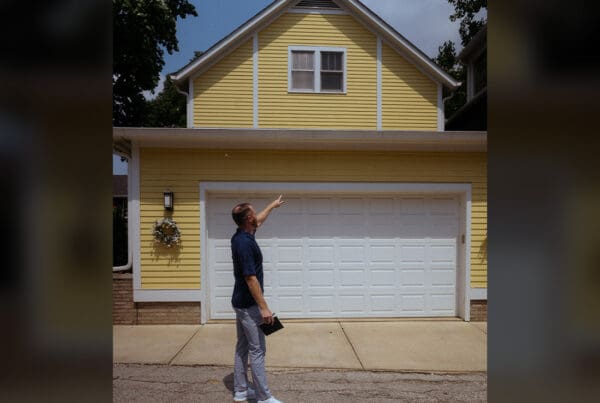 Buying a Home - Jackson Blevins Pointing at Outside of Home With Yellow Siding