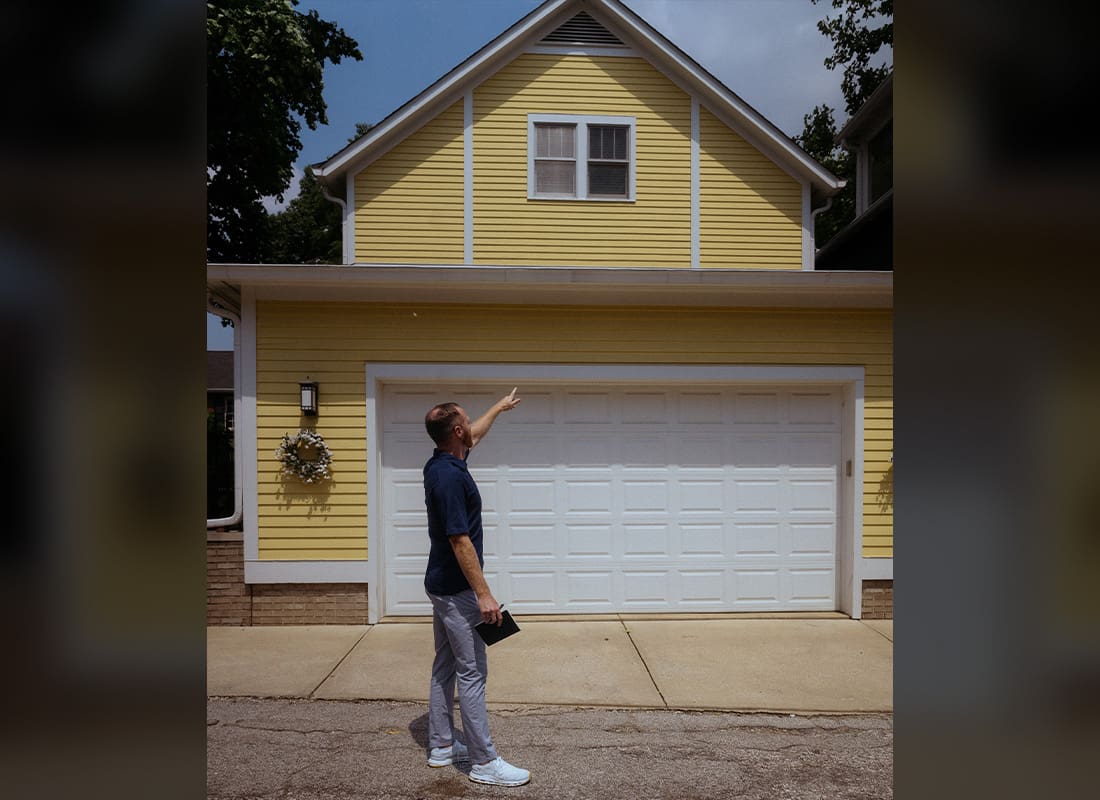 Buying a Home - Jackson Blevins Pointing at Outside of Home With Yellow Siding